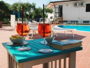 two wine glasses on a table next to a pool at Medimare Residence Club in Patti