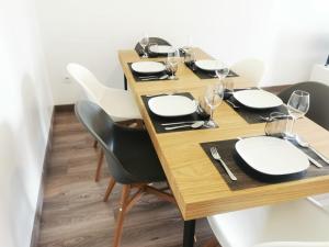 una mesa con sillas, platos y copas de vino en Appartement Jelyad Mallard proche Disney, en Chanteloup-en-Brie