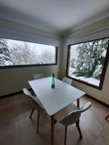 a dining room with a white table and two windows at Pacha Home By A.M.A in San Carlos de Bariloche
