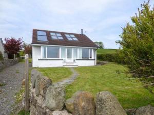 a white house with windows and a stone fence at Bay View Cottage in Grange Over Sands