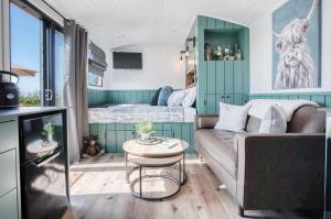 uma pequena sala de estar com um sofá e uma cama em Willows Rest - 1 Bed Shepherds Hut - Pentlepoir em Saundersfoot