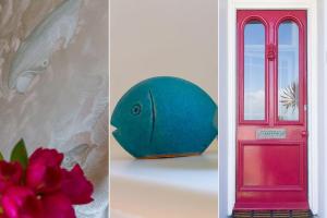 a red door and a blue fish next to a flower at High Noon in St Ives