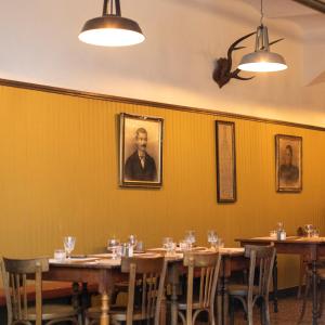 a dining room with wooden tables and a portrait of a man at Auberge des braconniers in Ampus