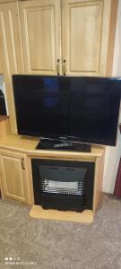 a large flat screen tv on a wooden stand at Beachside, Family-friendly, WiFi, 6 berth Caravans in Ingoldmells