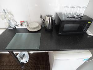 a black counter top with a microwave and plates at Richmond House in Southport