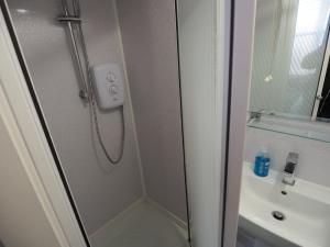 a shower with a glass door next to a sink at Richmond House in Southport