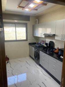 uma cozinha com armários brancos e uma máquina de lavar e secar roupa em Appart Hicham em Tânger