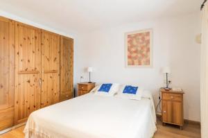 a bedroom with a white bed and wooden cabinets at Disfruta del mar antes de que lleguen las multitudes in L'Escala