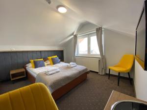 クリニツァ・モルスカにあるHotel Krynicaのベッドと黄色い椅子が備わるホテルルームです。
