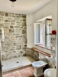 La salle de bains est pourvue de toilettes et d'un mur en pierre. dans l'établissement Intero alloggio campagna Lucca, à Capannori