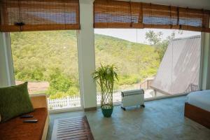 Un dormitorio con una gran ventana con una planta en Queenmary cottages, en Nanu Oya