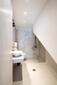La salle de bains blanche est pourvue d'un lavabo et de toilettes. dans l'établissement Ennea suites-Space suite, à Flámbouras