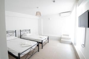Ennea suites-Space suite في Flámbouras: سريرين في غرفة بيضاء مع تلفزيون