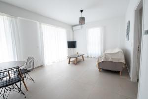 Ennea suites-Space suite في Flámbouras: غرفة معيشة بيضاء مع طاولة وكراسي