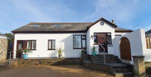 a white house with a wooden door and stairs at Trevelyan in St Ives