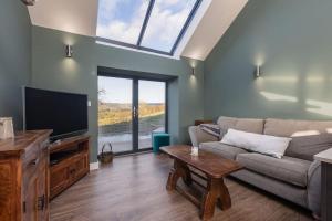 sala de estar con sofá y TV en Green End Farm Cottages The Stables en Goathland