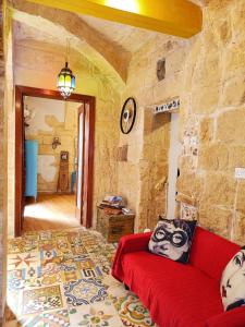 a living room with a red couch and a stone wall at Fusion Homestay Accommodation in Mosta