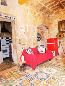a living room with a red couch and a stone wall at Fusion Homestay Accommodation in Mosta