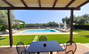 eine Terrasse mit einem Tisch, Stühlen und einem Pool in der Unterkunft Lefkogea Villas & Apartments in Tsoukaladhes
