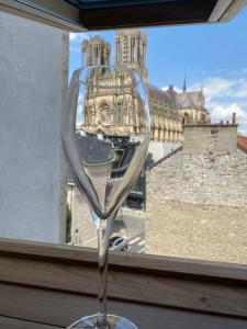um copo de vinho em frente a uma janela com um edifício em Duplex hammam au pied de la Cathédrale avec vue em Reims