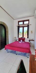 a bedroom with a large red bed with a window at Balinda Rooms & Villa in Lovina