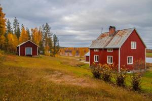 une grange rouge dans un champ à côté d'une maison dans l'établissement COZY Home with LAKE view-free WiFi - free SAUNA, à Överkalix