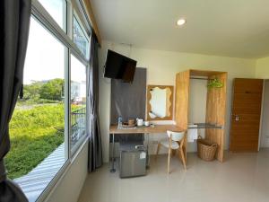ナイヤンビーチにあるDwell Phuket Airport Hotel at Naiyangのデスクと窓が備わる小さな客室です。