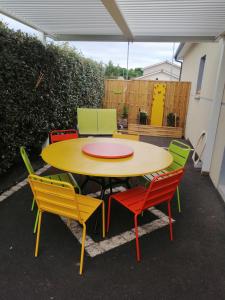 een gele tafel met kleurrijke stoelen eromheen bij Maison contemporaine à Artigues-près-Bordeaux in Artigues-près-Bordeaux