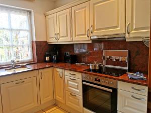 uma cozinha com armários brancos e um forno com placa de fogão em Ferienhaus Gartower See em Gartow