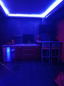 a dark room with a kitchen with a counter and stools at L'instant romance Le Romantique in Castelnaudary +10 photos