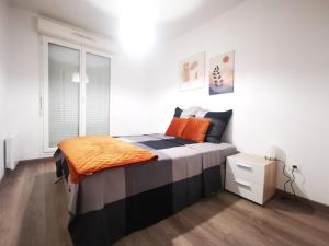 Un dormitorio con una cama con una manta naranja. en Appartement Jelyad Mallard proche Disney, en Chanteloup-en-Brie