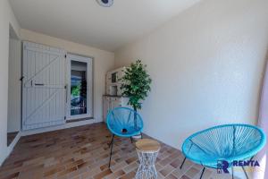 a room with two blue chairs and a kitchen at La Perle WIFI Plain Pied Proche Mer in Saint Cyprien Plage