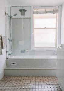 baño blanco con bañera y ventana en Sunny Corner Holiday Home, en Crescent Head