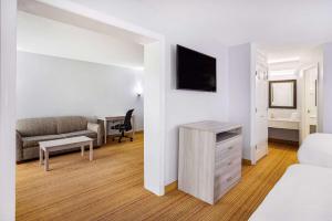 Habitación con cama, sofá y escritorio. en Days Inn & Suites by Wyndham Colonial, en Williamsburg