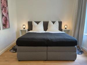 Una cama con edredón negro y almohadas. en Prinzenhof Suite, en Bad Harzburg 2 fotos más