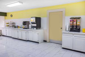 a kitchen with white cabinets and a yellow wall at Days Inn & Suites by Wyndham Colonial in Williamsburg