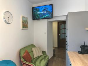 a living room with a green chair and a tv on the wall at The Bridge of Lies Apartment in Sibiu