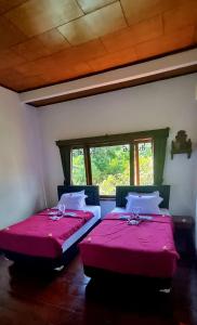 two beds in a room with red sheets and a window at Balinda Rooms & Villa in Lovina