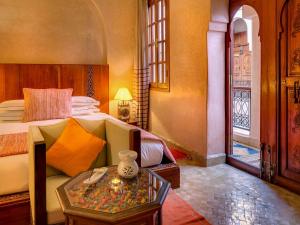 ein Schlafzimmer mit einem Bett und einem Tisch mit einer Vase darauf in der Unterkunft Marrakech Riads, Angsana Heritage Collection in Marrakesch