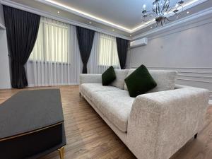 ein Wohnzimmer mit einem Sofa mit zwei grünen Kissen in der Unterkunft Home Apartment Luxe in Schymkent