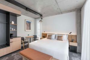 a bedroom with a large white bed and a table at Vibe Hotel Adelaide in Adelaide