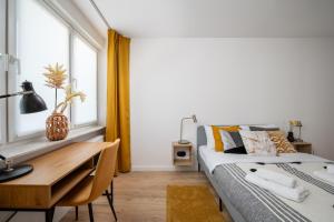 a bedroom with a bed and a desk and a window at Ochota Yellow Apartment in Warsaw