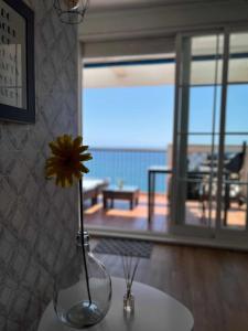 a vase with a yellow flower sitting on a table at Ático con terraza frente al mar Playa Zapillo in Almería