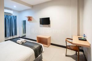 um quarto com uma cama, uma secretária e uma televisão em New Gentala Hotel Mitra RedDoorz em Medan