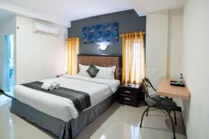 棉蘭的住宿－New Gentala Hotel Mitra RedDoorz，一间卧室配有一张大床、一张桌子和一张桌子