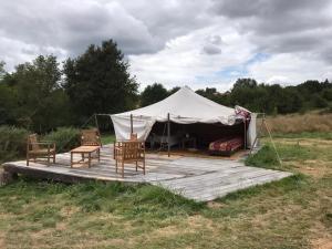 a tent with chairs and a bed in a field at Tamana Tuquet Tentes Mauritannienne in Bergerac