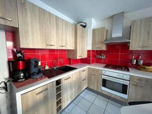 a kitchen with wooden cabinets and a red wall at Havre de paix Annécien in Meythet