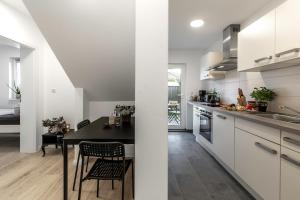 a kitchen with white cabinets and a black table and chairs at Arkadia Apartments-Schwissel-Bad Segeberg in Schwissel +21 photos