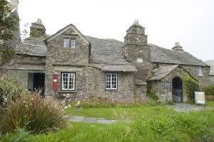 una vieja casa de piedra con una puerta roja en King Arthurs Arms en Tintagel