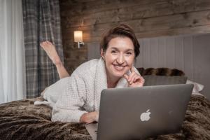 Luxury Chalet Na Stromym Wzgórzu z sauną i balią في شتوروك: امرأة مستلقية على سرير مع جهاز كمبيوتر محمول